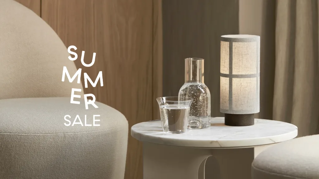 "SUMMER SALE" 텍스트가 있는 현대적인 거실 풍경. 안락의자, 대리석 협탁, 물, 원통형 램프가 보입니다.