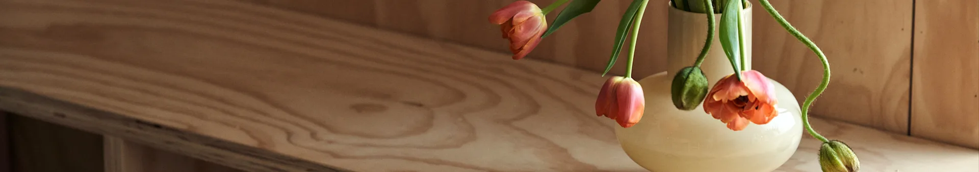 노르딕네스트에서 인테리어 디자인 팁과 최신 인테리어 트렌드에 대해 읽어보세요. 여기에는 오렌지색 튤립이 담긴 마리메꼬의 노란색 꽃병이 보입니다
