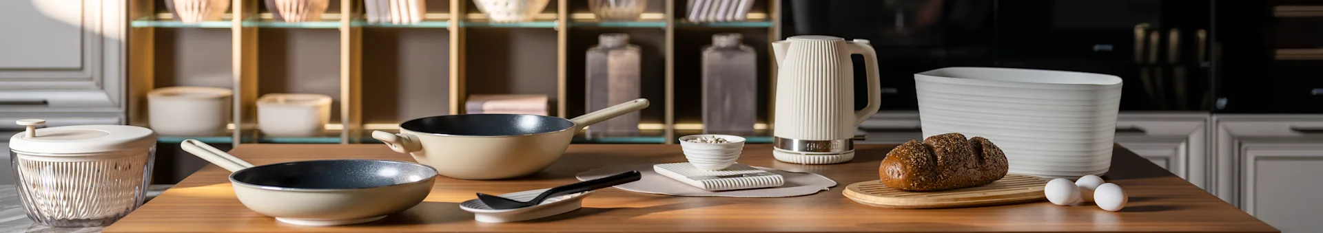 베이지색 프라이팬, 흰색 립 주전자, 도마 위 씨앗 빵, 달걀이 있는 주방 조리대. 현대적인 주방 액세서리.