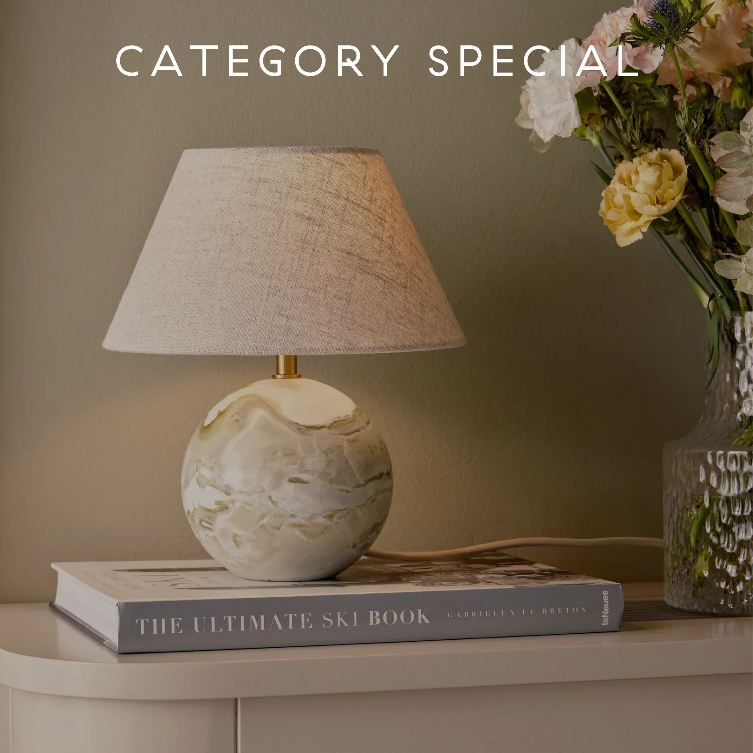 대리석 구형 받침과 밝은 천 갓이 있는 테이블 램프가 책과 꽃 옆에 놓여 있으며, 'CATEGORY SPECIAL' 텍스트가 있다.