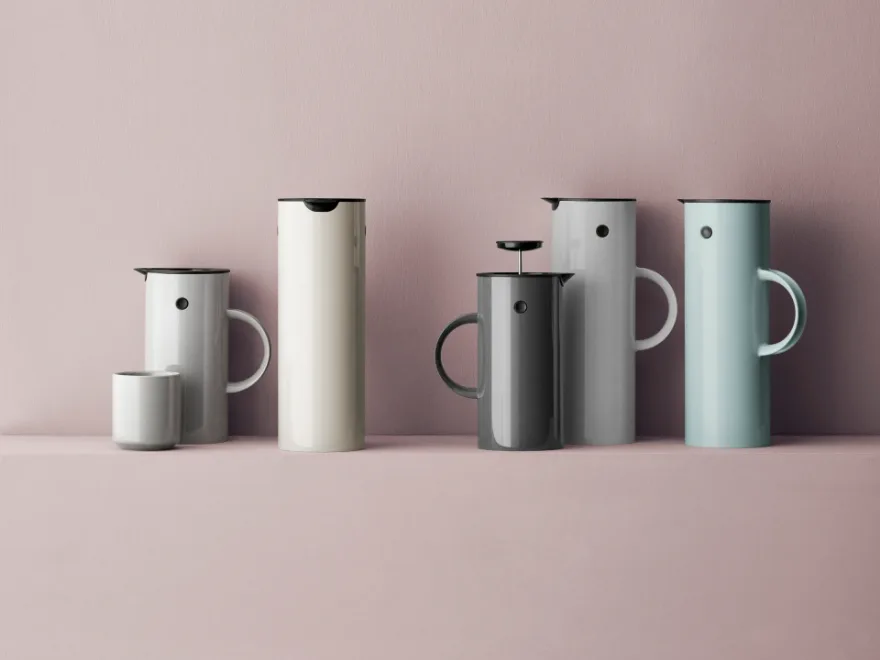 다양한 차분한 색상의 현대적인 보온병과 프렌치 프레스, 핑크 배경에 어울리는 컵.